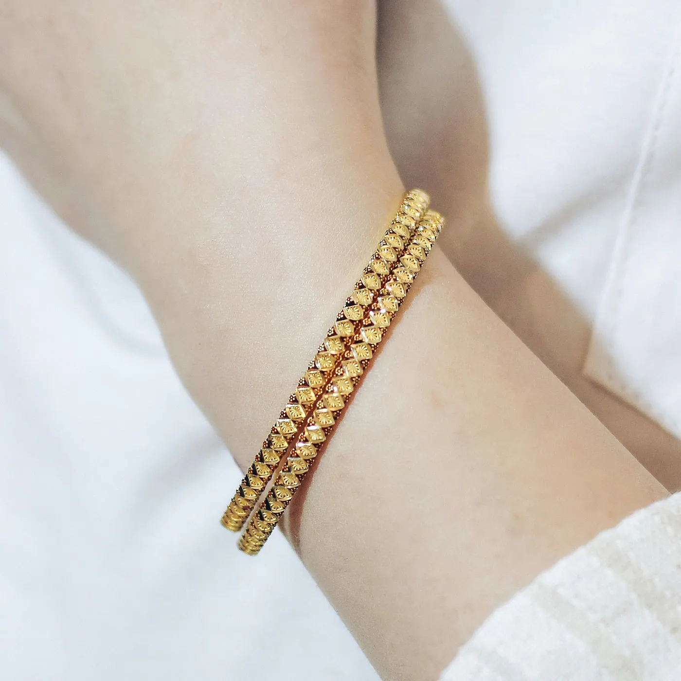 Zwei goldene Perlenarmbänder am Handgelenk